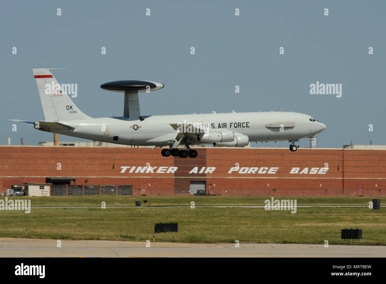 A Boeing E-3G Airborne Warning and Control System aircraft on final approach to land June 16, 2017, Tinker Air Force Base, Oklahoma. The large building behind the E-3 AWACS is building 3001, a former Douglas Aircraft manufacturing plant during World War II, now used by the Oklahoma City Air Logistics Complex and its parent organization the Air Force Sustainment Center. The E-3 is operated by the 552nd Air Control Wing, Air Combat Command, from Tinker AFB where heavy maintenance of the E-3 airframe and engines is also conducted by the OC-ALC. (U.S. Air Force photo/Greg L. Davis) Stock Photo