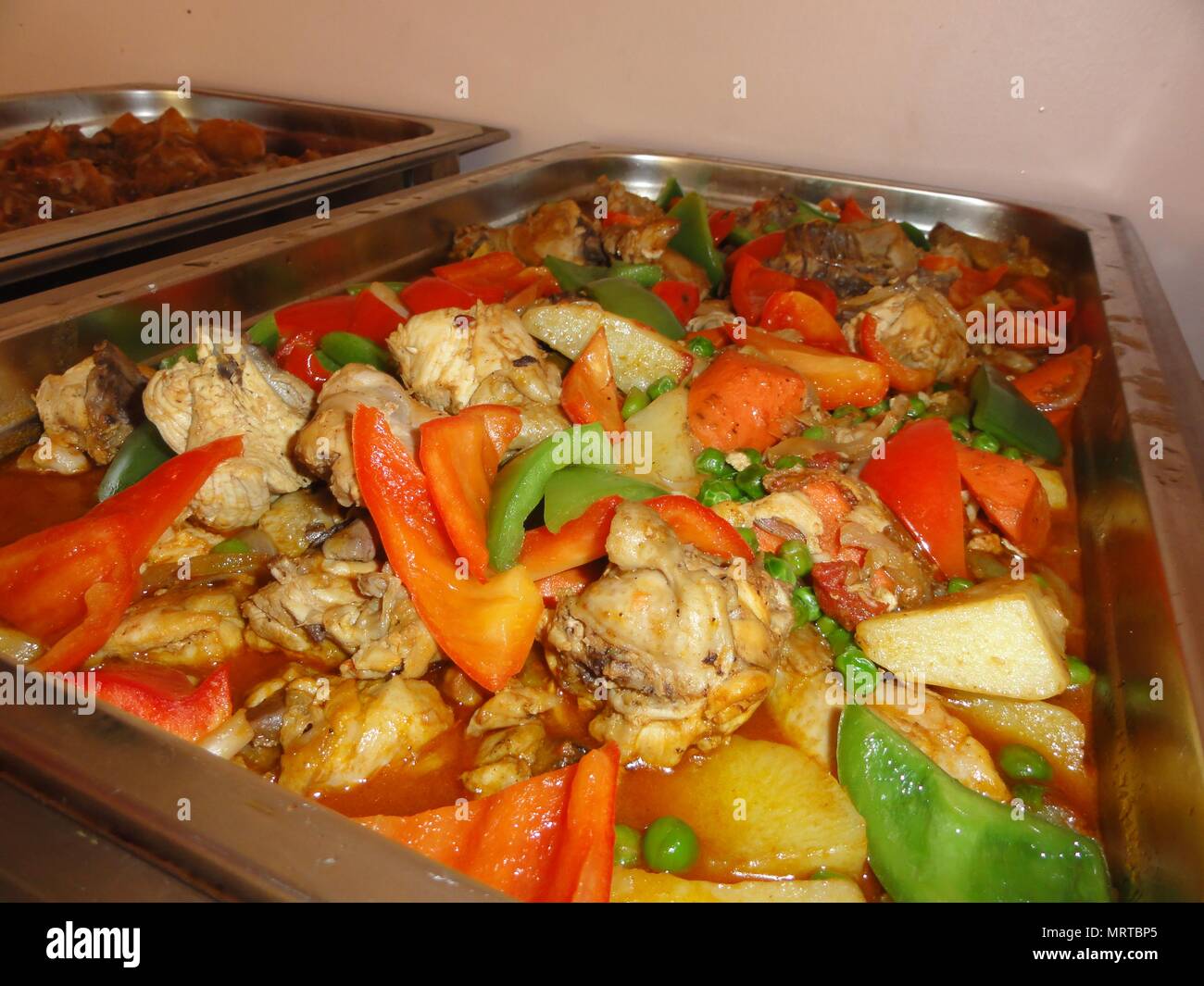 Chicken afritada is a popular favorite dish in the Philippines where chicken pieces are cooked in tomato sauce with potatoes, carrots, bell peppers, a Stock Photo