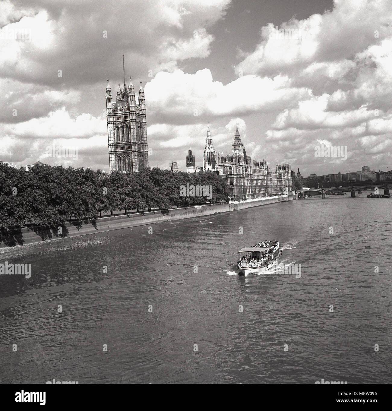 1960s, historical, view down the River Thames, London, showing on the left, the Palace of Westminster, the meeting place of the UK Government. At the palace are the two Houses of Parliament, the House of Commons and the House of Lords. Stock Photo