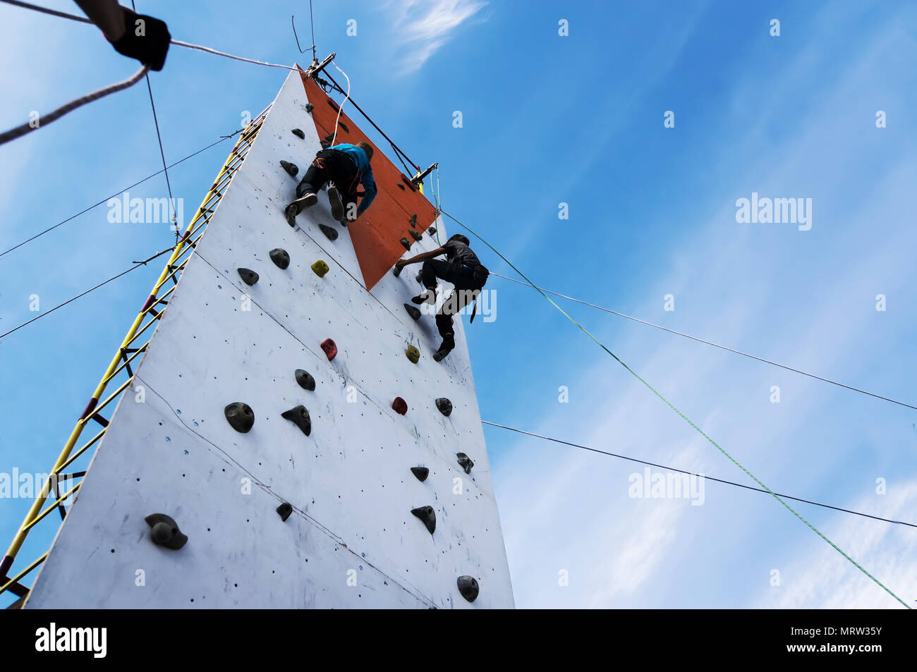 boy learning to climb the rock wall outside in the park. Bouldering