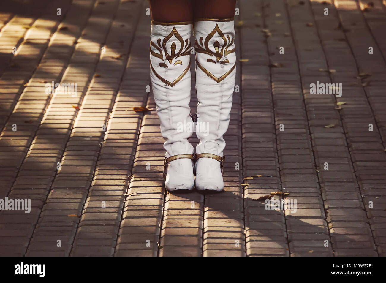 White ladies boots are on the pavement. A girl in womens high cowboy boots stands alone and waits Stock Photo