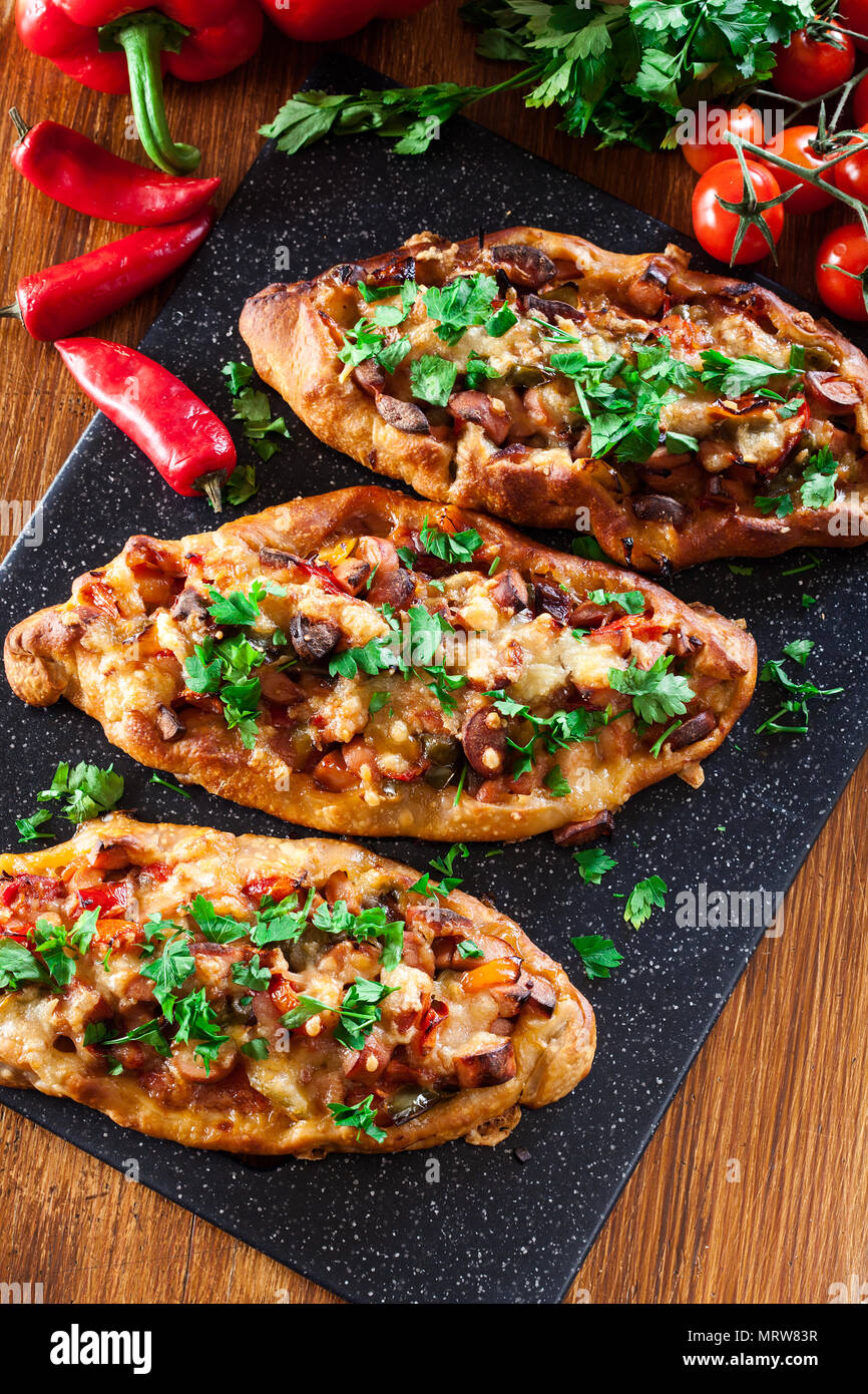 Traditional Turkish pide with meat and vegetables on cutting board. Top ...