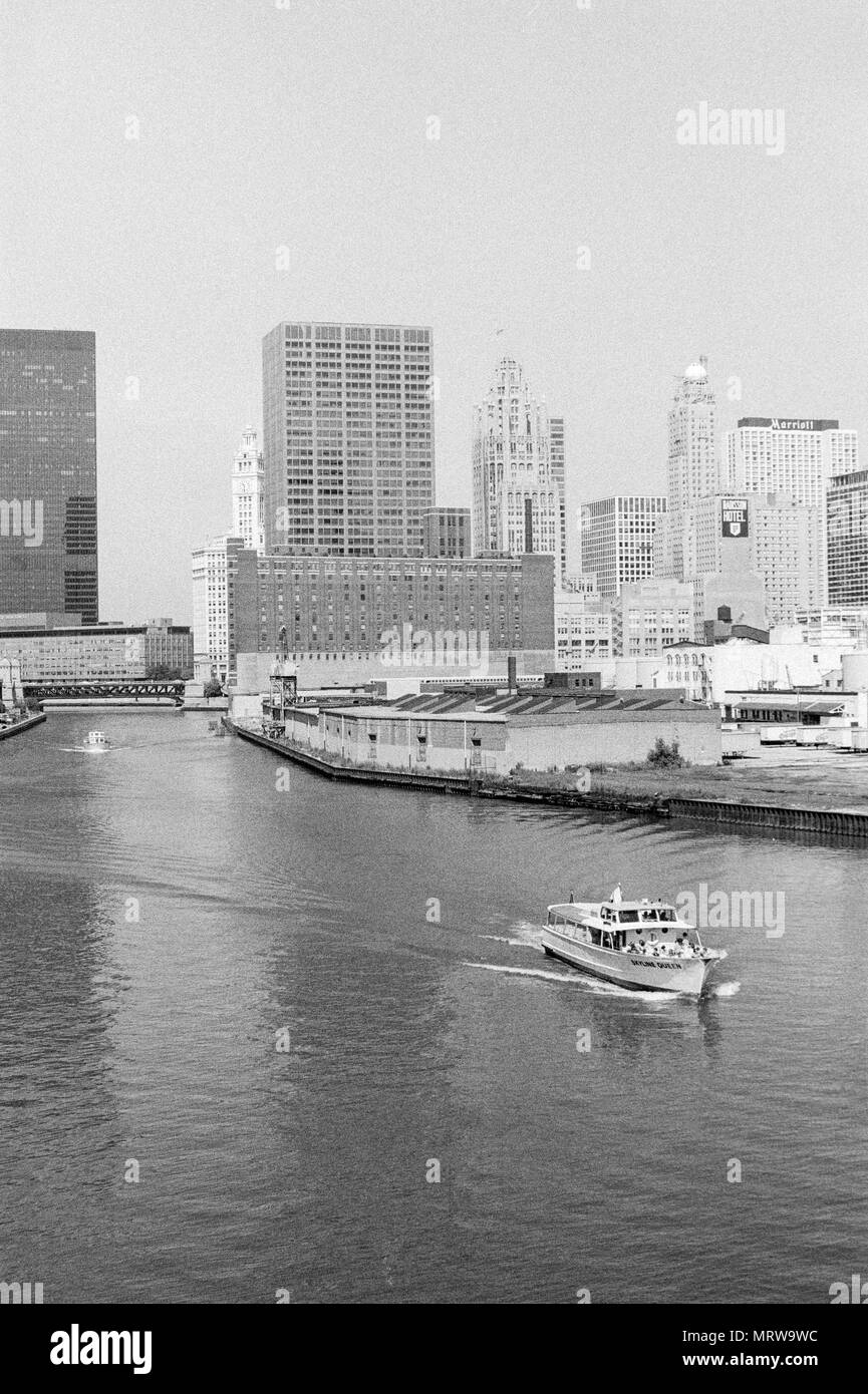 View of Chicago, 1980. The Marriott Hotel and Radisson Hotel in the background. Trailers for the Chicago Tribune newspaper wait to be loaded, and the 'Skyline Queen' please boat in the foreground. Stock Photo