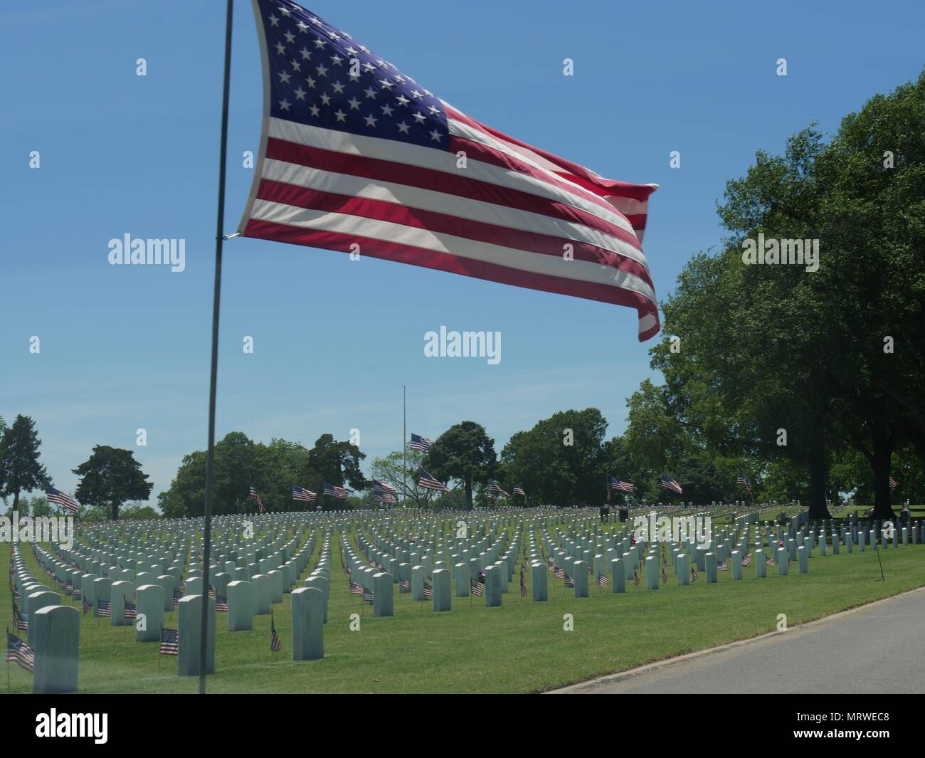 A big United States flag at half staff and small US flags wave in the
