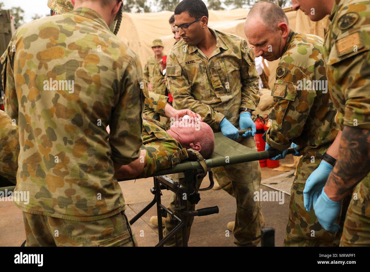 Australian Army medics with 17th Combat Service Support Brigade unload a patient with a simulated shrapnel wound from an ambulance during a mass casualty exercise at Williamson Air Field, Shoalwater Bay Training Area, Queensland, Australia, July 8, 2017 during Talisman Saber 17. Soldiers with 17th CSS Brigade conducted a mass-casualty exercise at Williamson Air Field hospital to practice Role 2 advanced trauma care and procedures that are used in a deployed environment. Exercises like Talisman Saber provide effective and intense training to ensure our forces are capable, interoperable, deploya Stock Photo