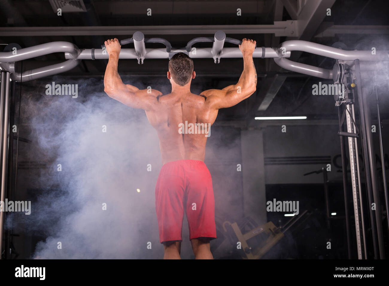 Strong young man doing pull up exercise on horizontal bar in gym Stock ...