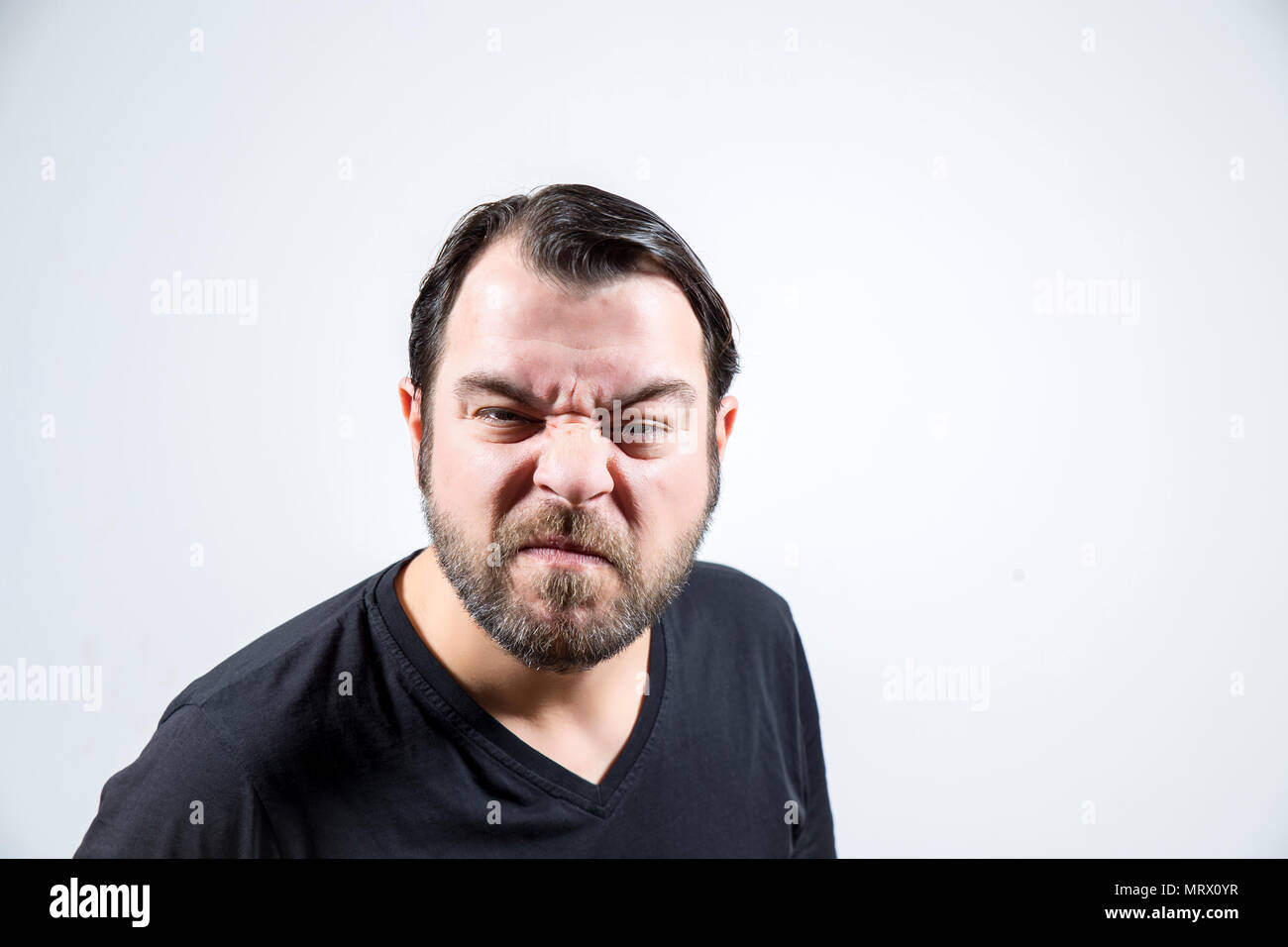 Adult man with frowning face is looking to the camera Stock Photo
