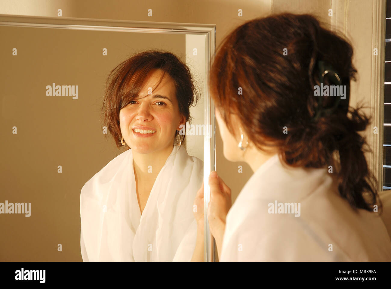Portrait of woman looking at the camera from her image reflected on a mirror. Stock Photo