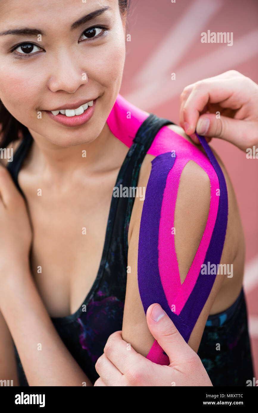 Woman taping with therapeutic tape on cinder track of stadium Stock Photo