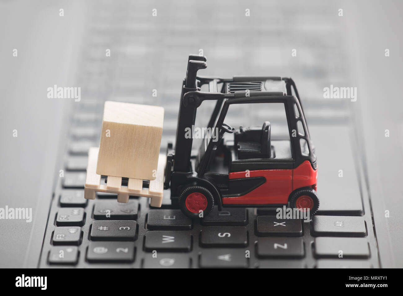 Forklift miniature with wooden block on laptop keyboard Stock Photo