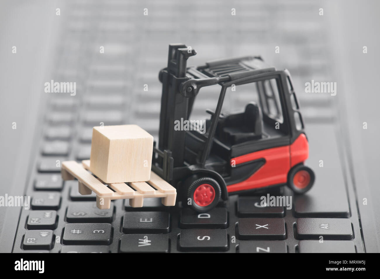 Forklift miniature with wooden block on laptop keyboard Stock Photo