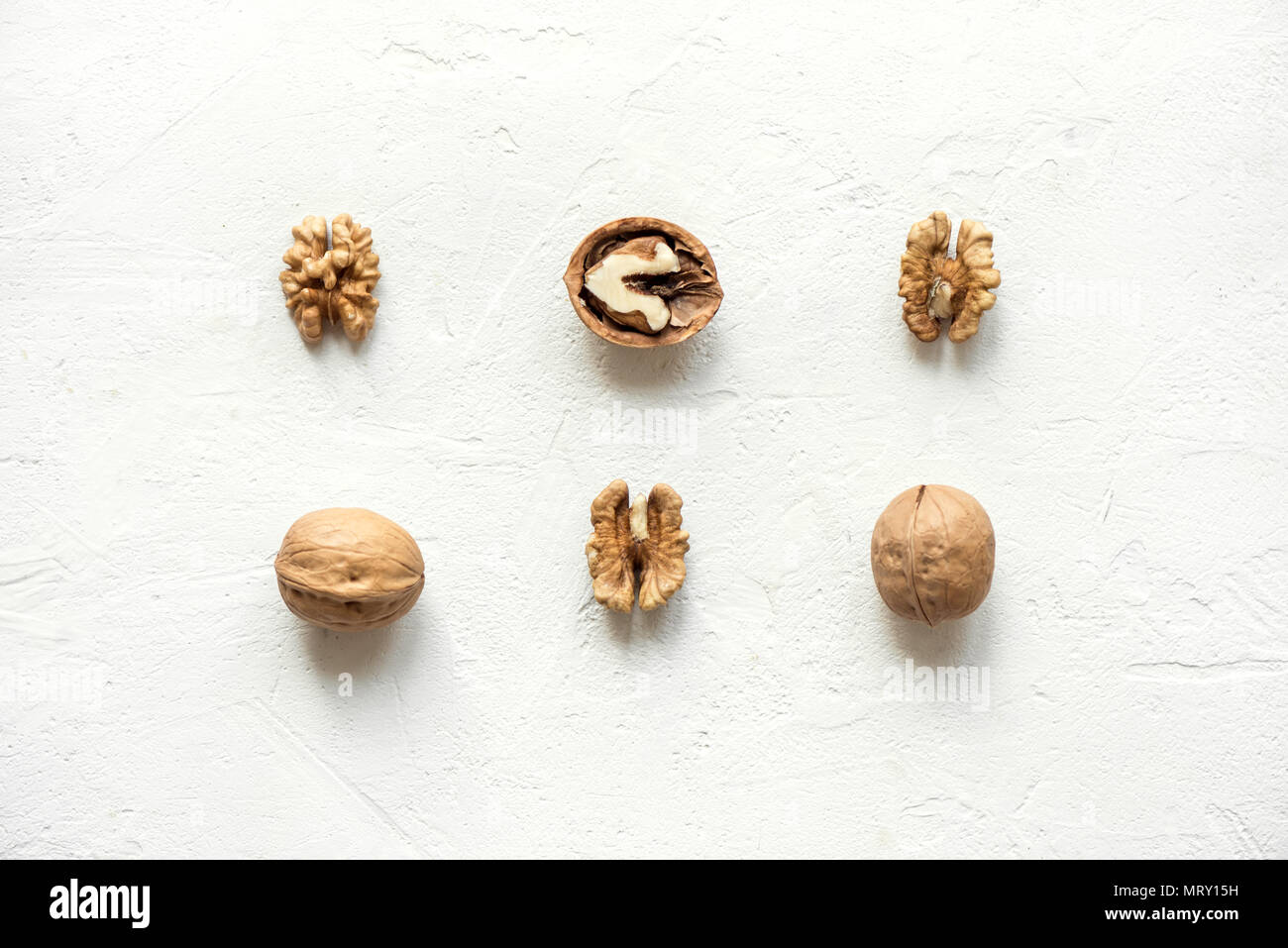 Walnuts on white background with shells and peeled as pattern, flat lay with copy space. Stock Photo