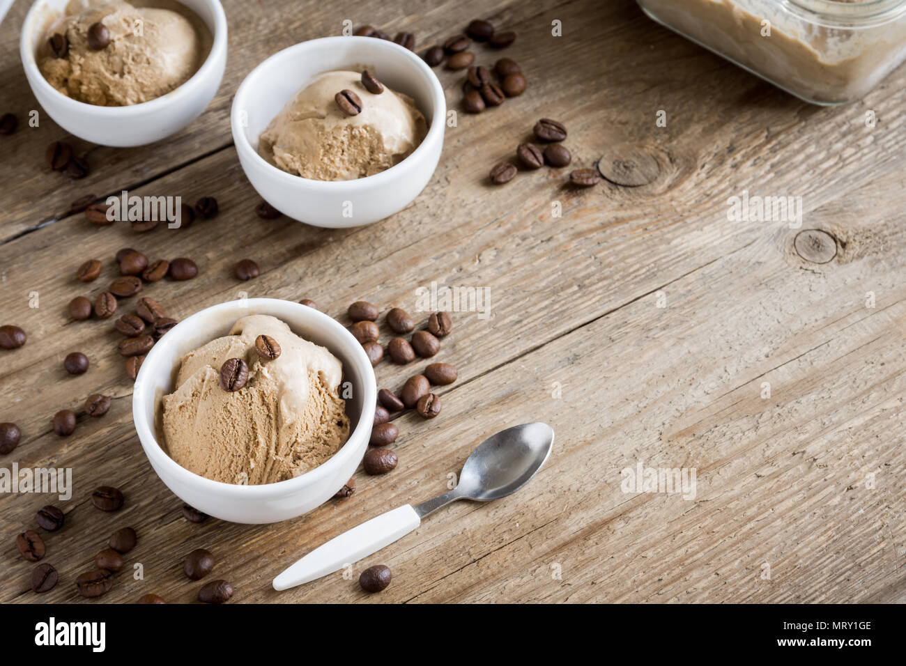 Coffee ice cream on wooden background, top view. Frozen coffee gelato ice cream with coffee beans and cinnamon - healthy summer dessert. Stock Photo