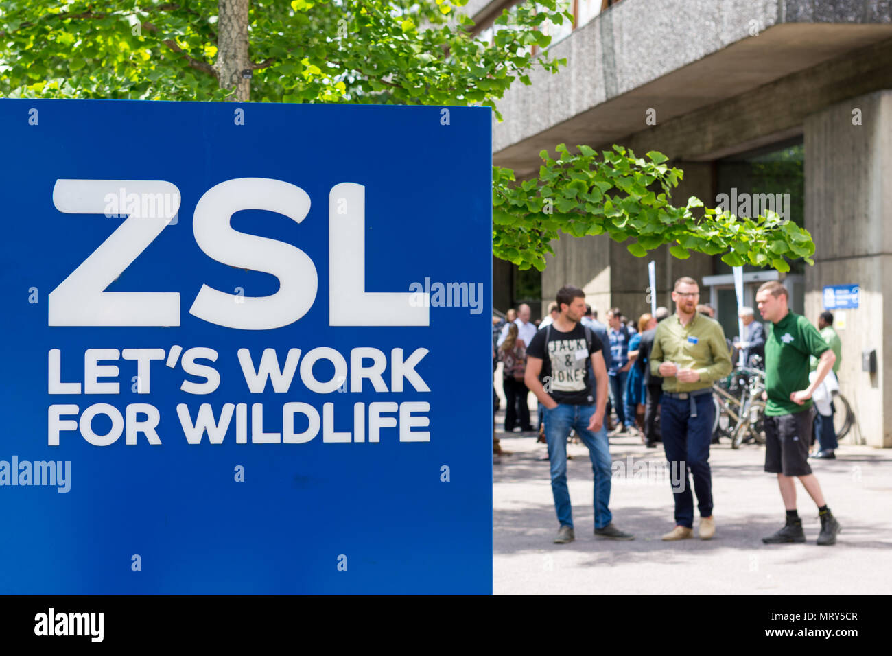 Zoological Society of London sign with three young men in the background. Stock Photo