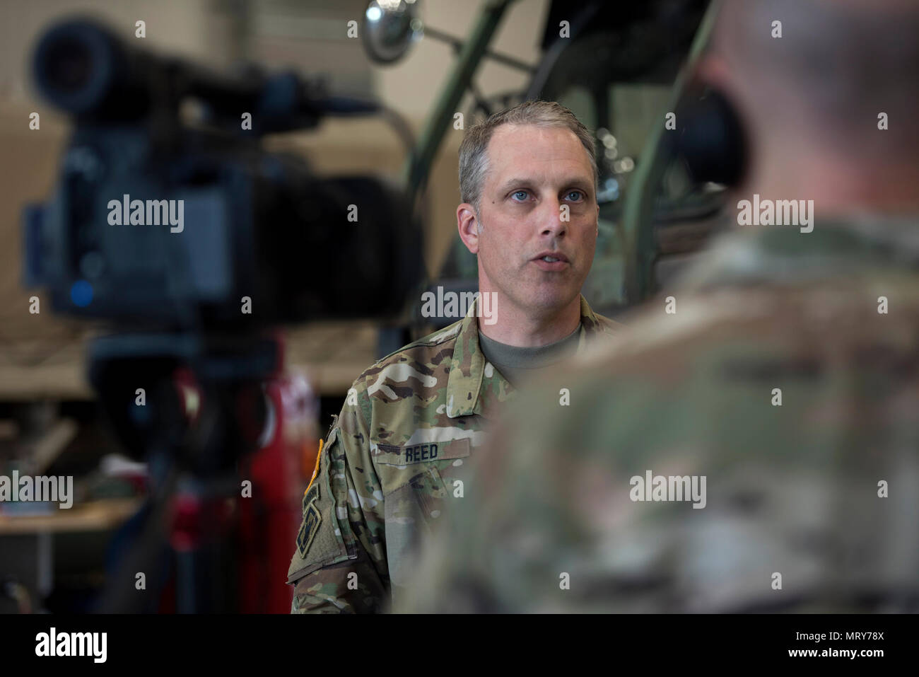 U.S. Army Chief Warrant Officer 2 Matthew Reed, construction engineer, Detachment 1, Garrison Support Command, Vermont National Guard, gives an interview at the Vermont National Guard’s new vehicle maintenance shop ribbon cutting ceremony, North Hyde Park, Vt., July 12, 2017. Reed spoke about the facility being a Leadership in Energy and Environmental Design Silver certified building, which utilizes a geothermal ground source system to provide heating and cooling, as well as photovoltaic panels to reduce the demand of fuel and electric costs. (U.S. Air National Guard photo by Tech. Sgt. Sarah  Stock Photo