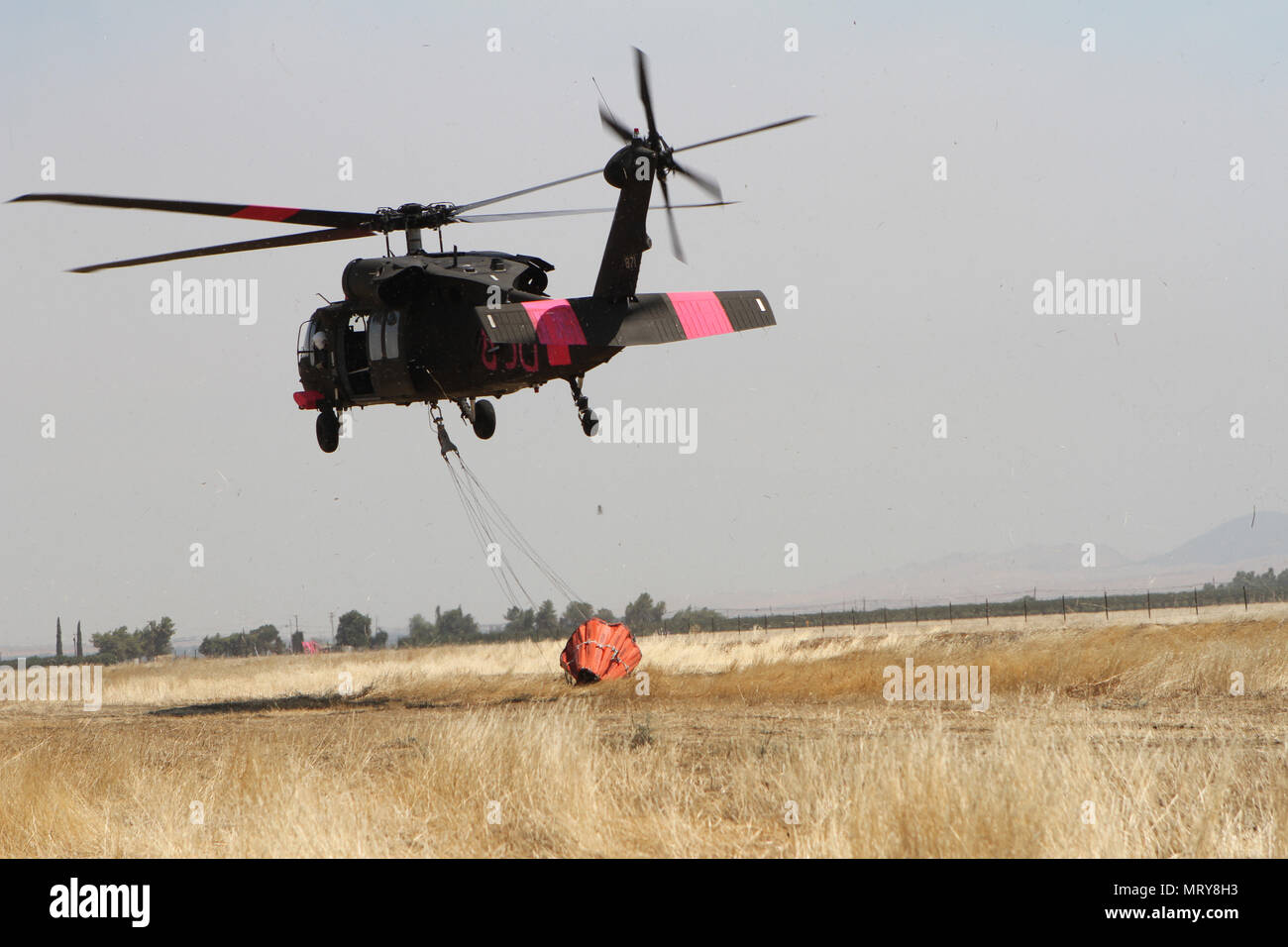 A California Army National Guard UH-60 Black Hawk departs the Coalinga Municipal Airport July 13 to battle the Garza Fire in Kings County, California. Five CalGuard Black Hawks responded to the Garza Fire, one of nearly two dozen wildfires torching the Golden State in mid-July 2017. It had already consumed more than 26,000 acres and was 30 percent contained, per the California Department of Forestry and Fire Protection (CAL FIRE). (Army National Guard photo/Staff Sgt. Eddie Siguenza) Stock Photo