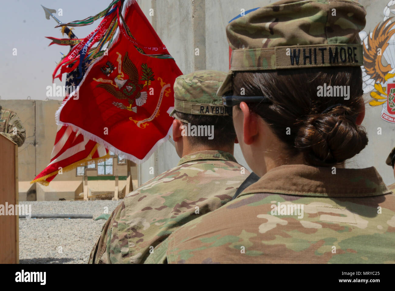 U.S. Army Capt. Kaitlin Whitmore, commander of Charlie Company, 215th Brigade Support Battalion, 3rd Armored Brigade Combat Team, 1st Cavalry Division, and her brother, U.S. Army Capt. Scott Rayburn, incoming commander of Alpha Company, 37th Engineer Battalion, 2nd Brigade Combat Team, 82nd Airborne Division, listen as 37th Eng. Bn. Commander Lt. Col. Sebastian Pastor addresses those in attendance at a change-of-command ceremony in Qayyarah West Airfield, Iraq, July 1, 2017. The siblings, who hail from Gainesville, Florida, both attended ROTC in college and were commissioned during the same we Stock Photo