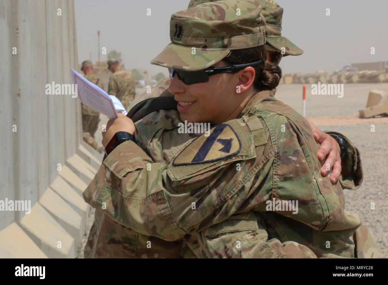 U.S. Army Capt. Kaitlin Whitmore, commander of Charlie Company, 215th Brigade Support Battalion, 3rd Armored Brigade Combat Team, 1st Cavalry Division, hugs her brother, U.S. Army Capt. Scott Rayburn, commander of Alpha Company, 37th Engineer Battalion, 2nd Brigade Combat Team, 82nd Airborne Division, at his change-of-command ceremony in Qayyarah West Airfield, Iraq, July 1, 2017. The siblings, who hail from Gainesville, Florida, both attended ROTC in college and were even commissioned during the same week in 2011. (U.S. Army photo by Staff Sgt. Leah R. Kilpatrick) Stock Photo