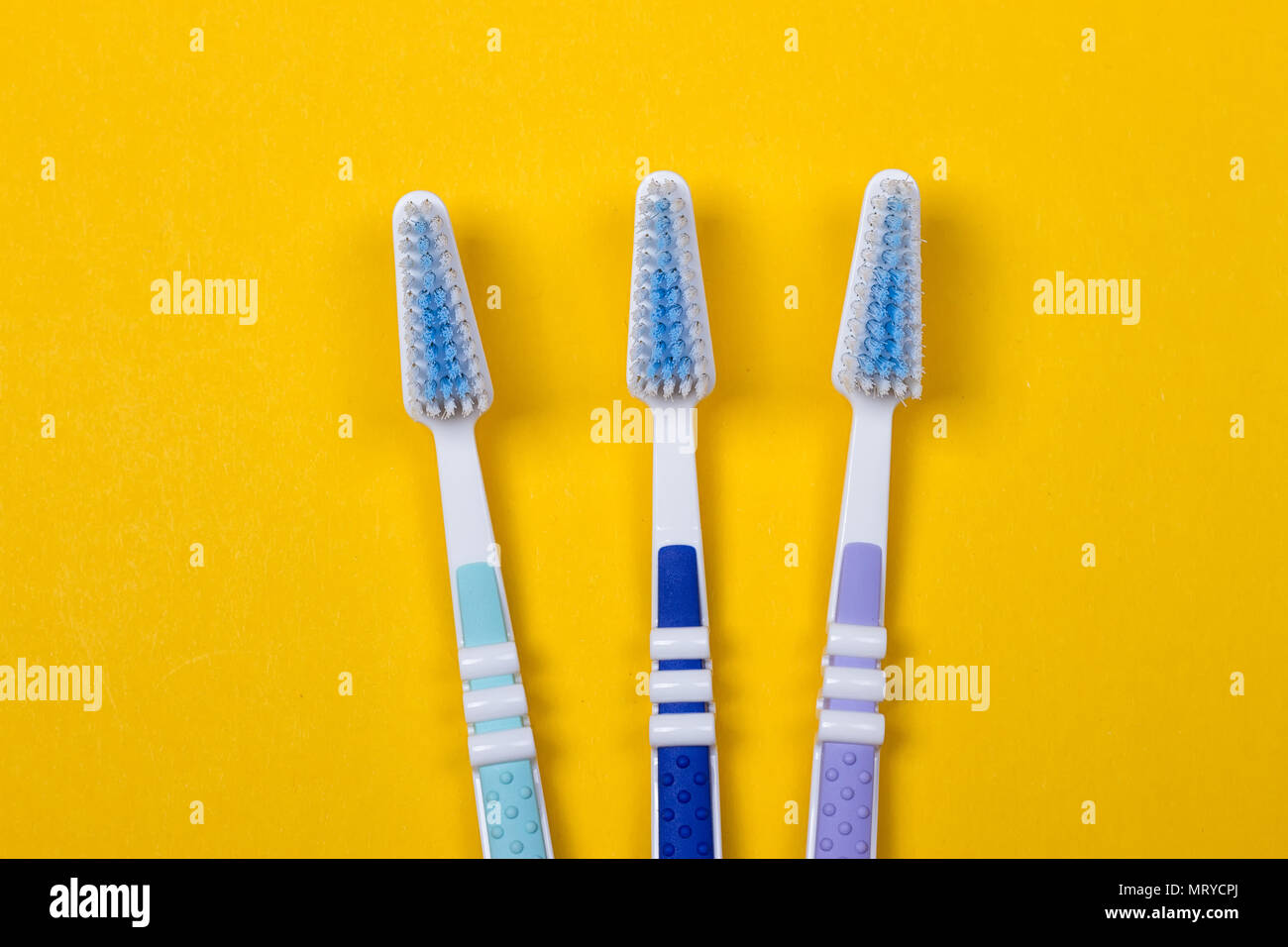 three Toothbrushes on the yellow background. Top view Stock Photo - Alamy
