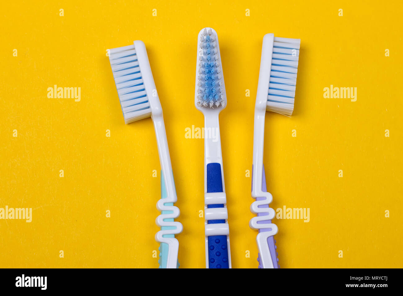 three Toothbrushes on the yellow background. Top view Stock Photo - Alamy