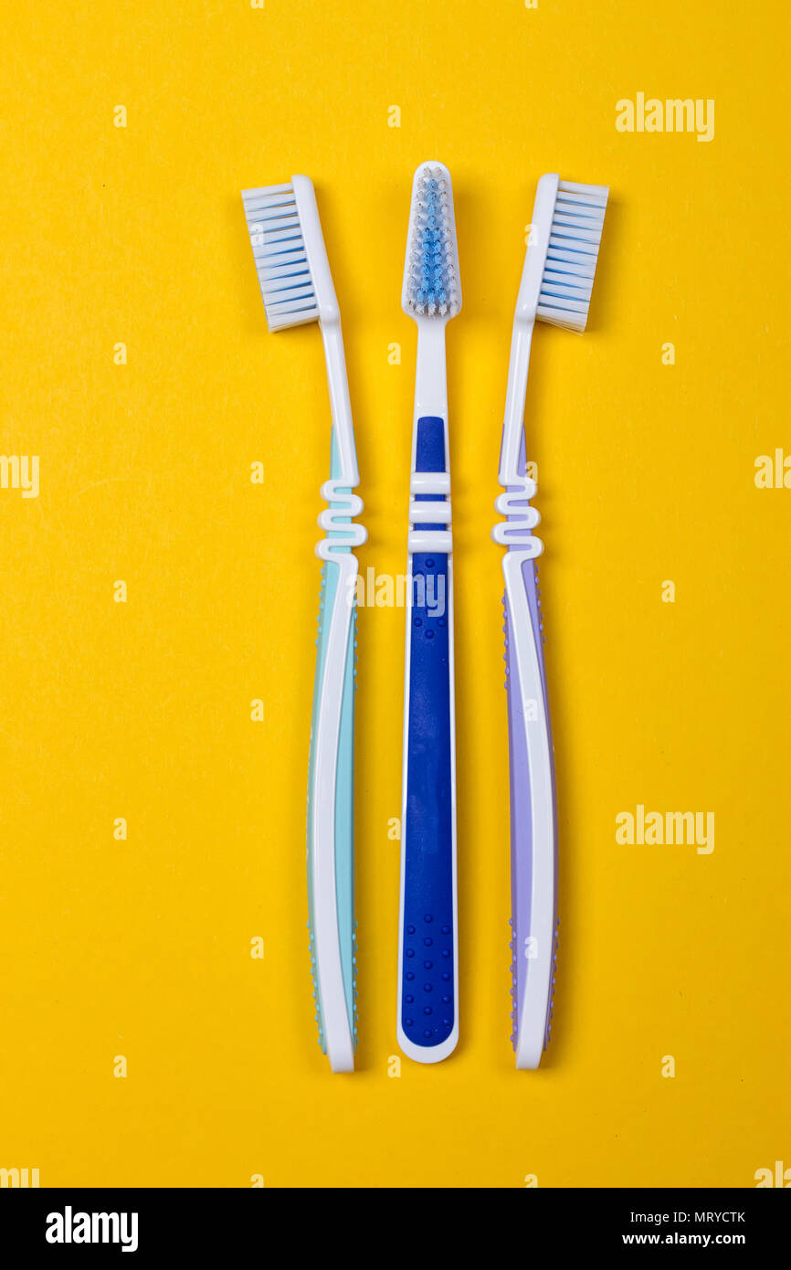 three Toothbrushes on the yellow background. Top view Stock Photo - Alamy