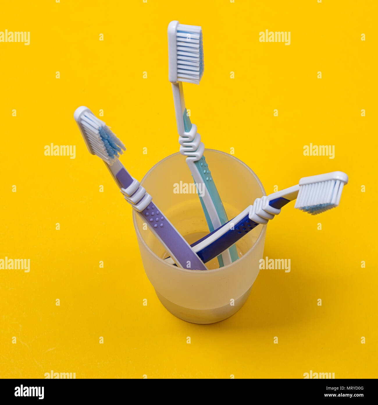 three toothbrushes in a glass on the yellow background. Top view Stock ...