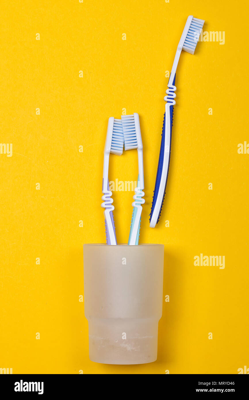 three toothbrushes in a glass on the yellow background. Top view Stock ...