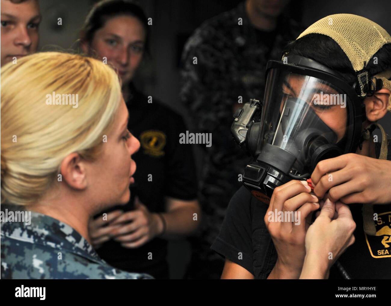 170714-N-YJ133-106 (POLARIS POINT, Guam) July 14, 2017 – Damage Controlman 1st Class Victoria Wells helps a sea cadet from U.S. Naval Sea Cadet Corps Marianas Division Guam don flash gear during a tour of submarine tender USS Emory S. Land (AS 39), July 14. Land and USS Frank Cable (AS 40), the U.S. Navy’s only two submarine tenders, both homeported in Apra Harbor, Guam, provide maintenance, hotel services and logistical support to submarines and surface ships in the U.S. 5th and 7th Fleet areas of operation. (U.S. Navy photo by Mass Communication Specialist 2nd Class Richard A. Miller/RELEASE Stock Photo