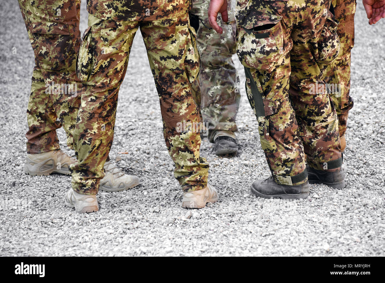 Group of soldiers wearing camouflage fatigues in a low angle view of their legs on gravel Stock Photo