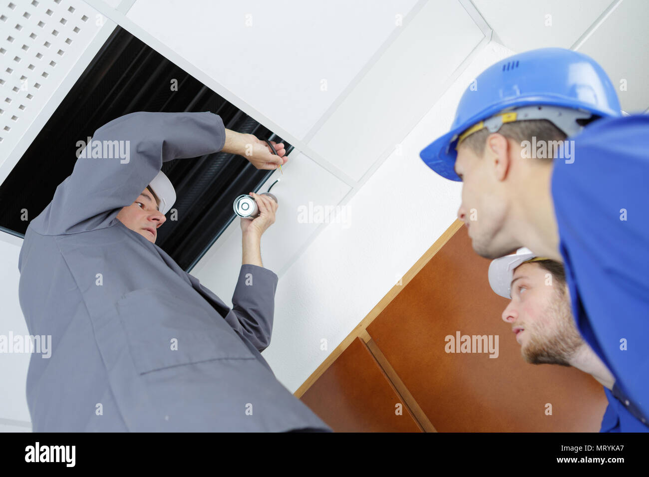 Electricians Installing Ceiling Lights In Domestic Home Stock