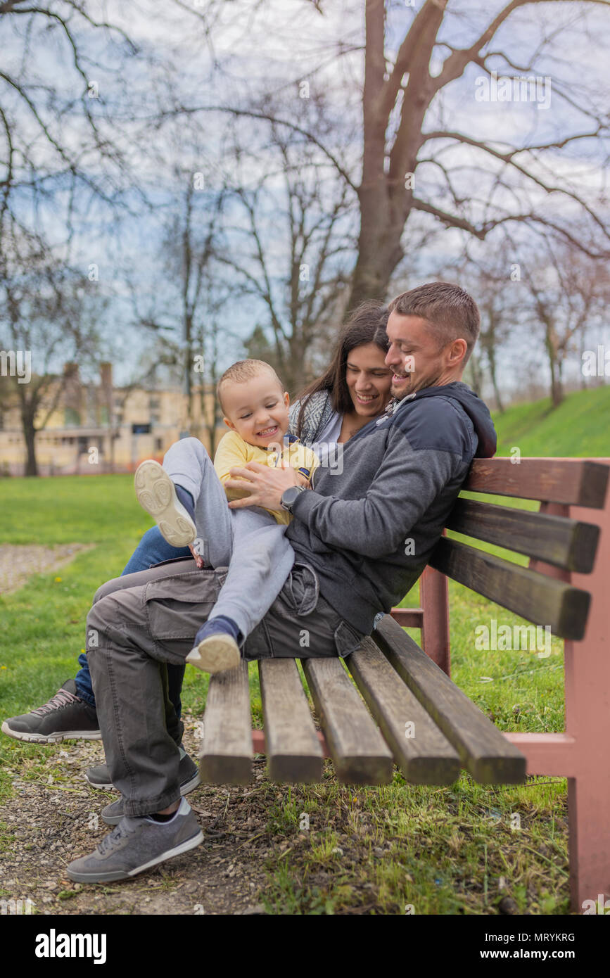 Parents having fun with their child in park. Beautiful family is having fun outside. Mom with dad are playing with their little son on playground. Ado Stock Photo