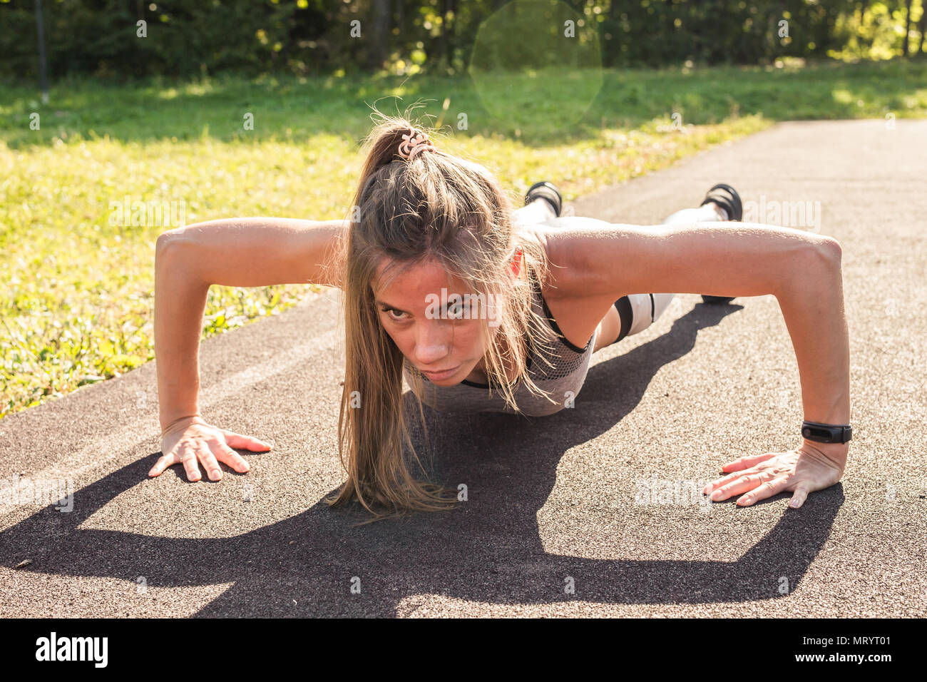 Fitness woman doing push-ups during outdoor cross training workout ...