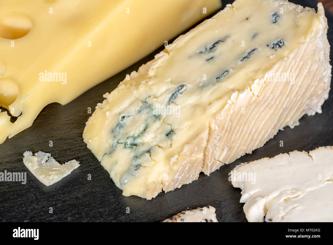 close up of big blue cheese with mold and various types of cheese on