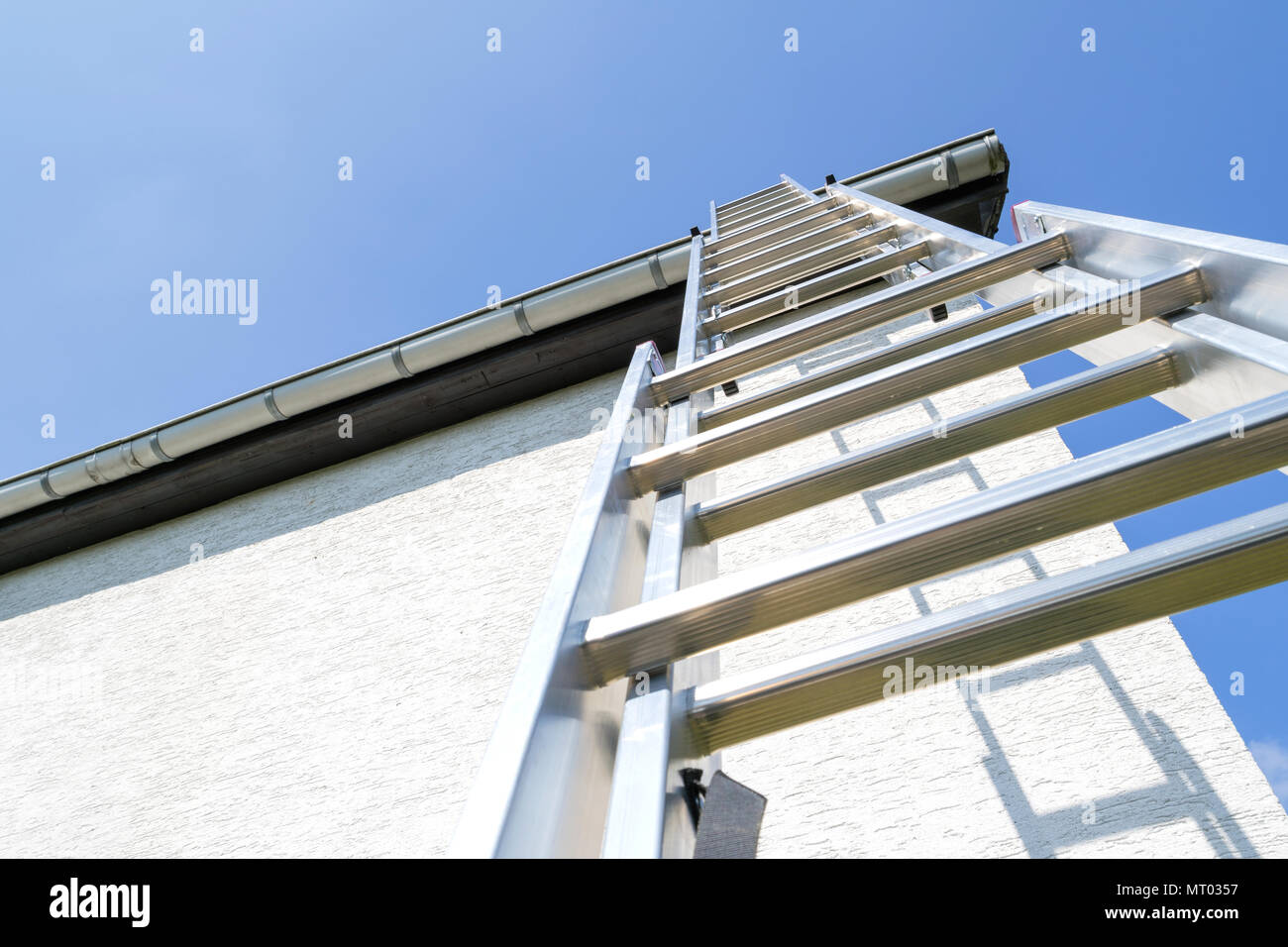 three section aluminum ladder leaning against house Stock Photo