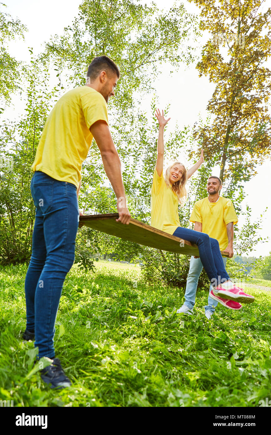 Young woman is cheeringly sitting on a wooden board at a teambuilding event Stock Photo