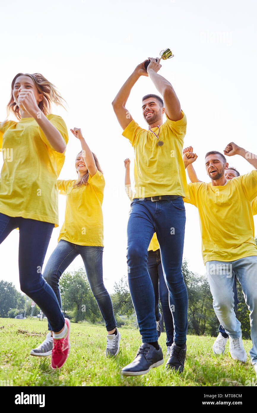 Happy winner team with cup on a meadow at the teambuilding workshop Stock Photo