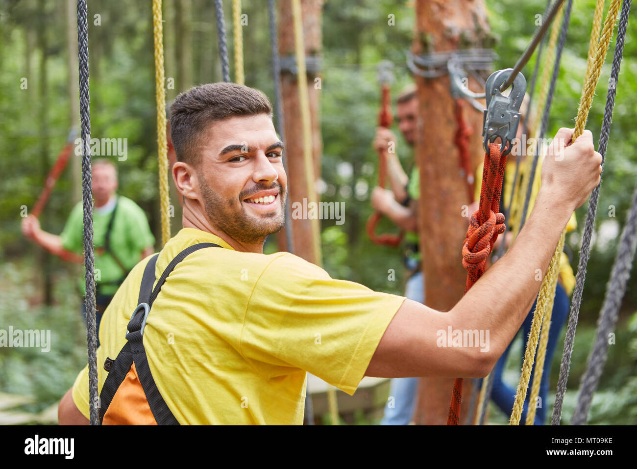 Young man in climbing forest or high ropes course at teambuilding event Stock Photo
