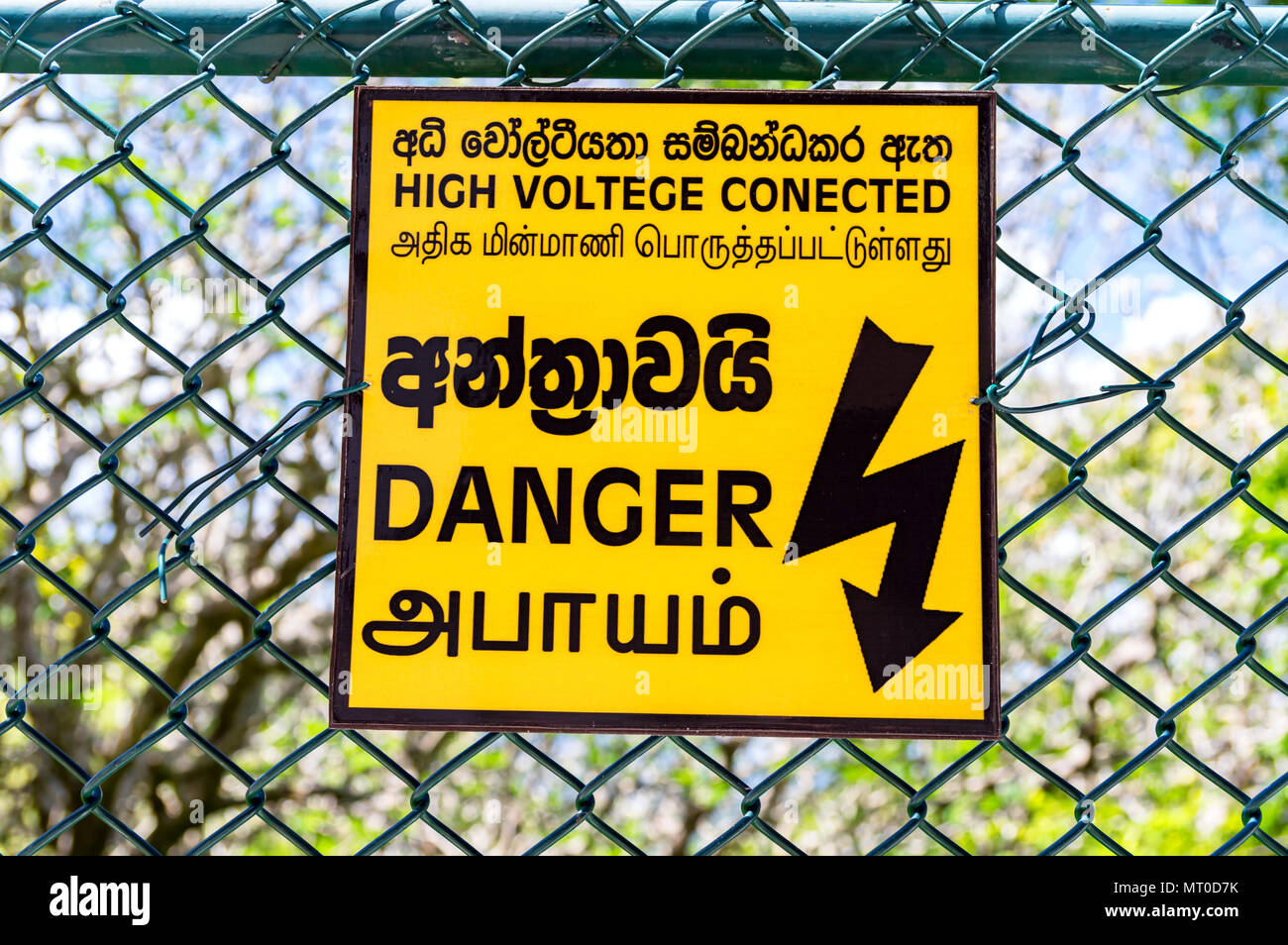 Yellow warning sign hanging on a wire fence Stock Photo