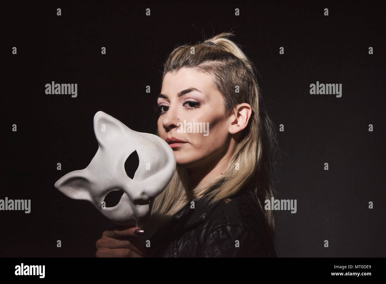 Young woman holding cats mask on dark background Stock Photo