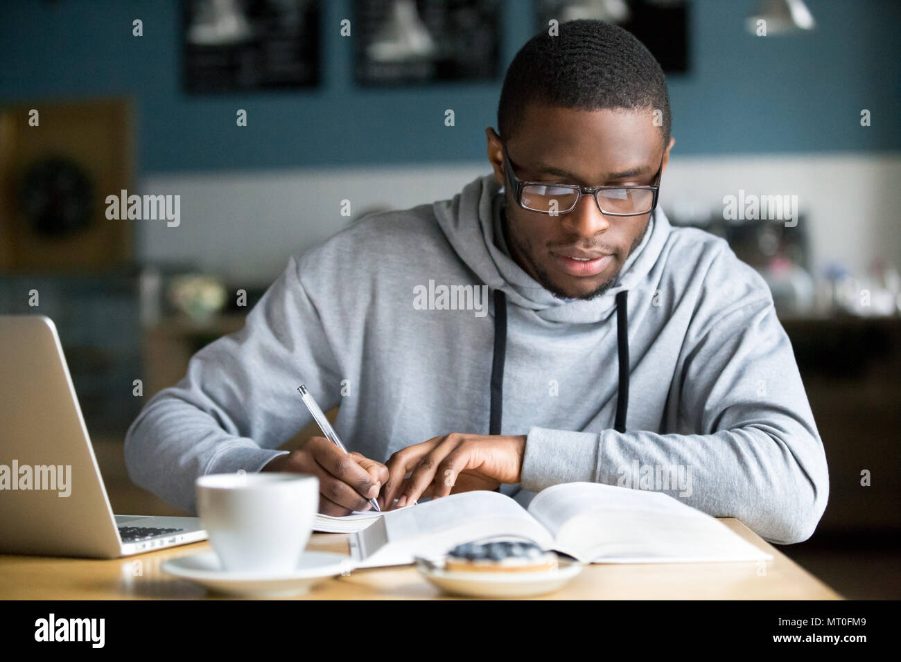 Focused millennial african student making notes while studying i Stock Photo