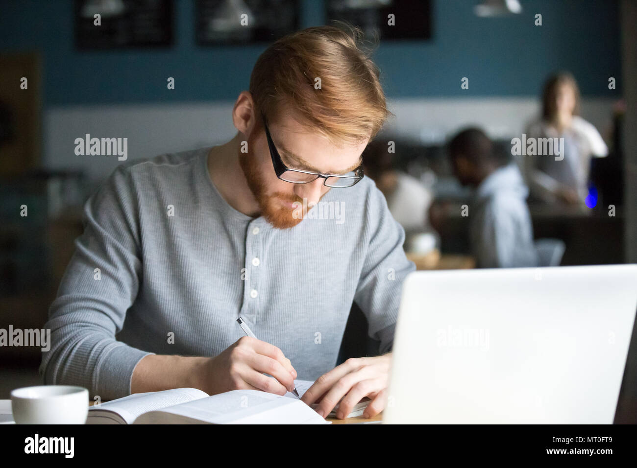 Focused millennial redhead student writing making notes studying Stock Photo