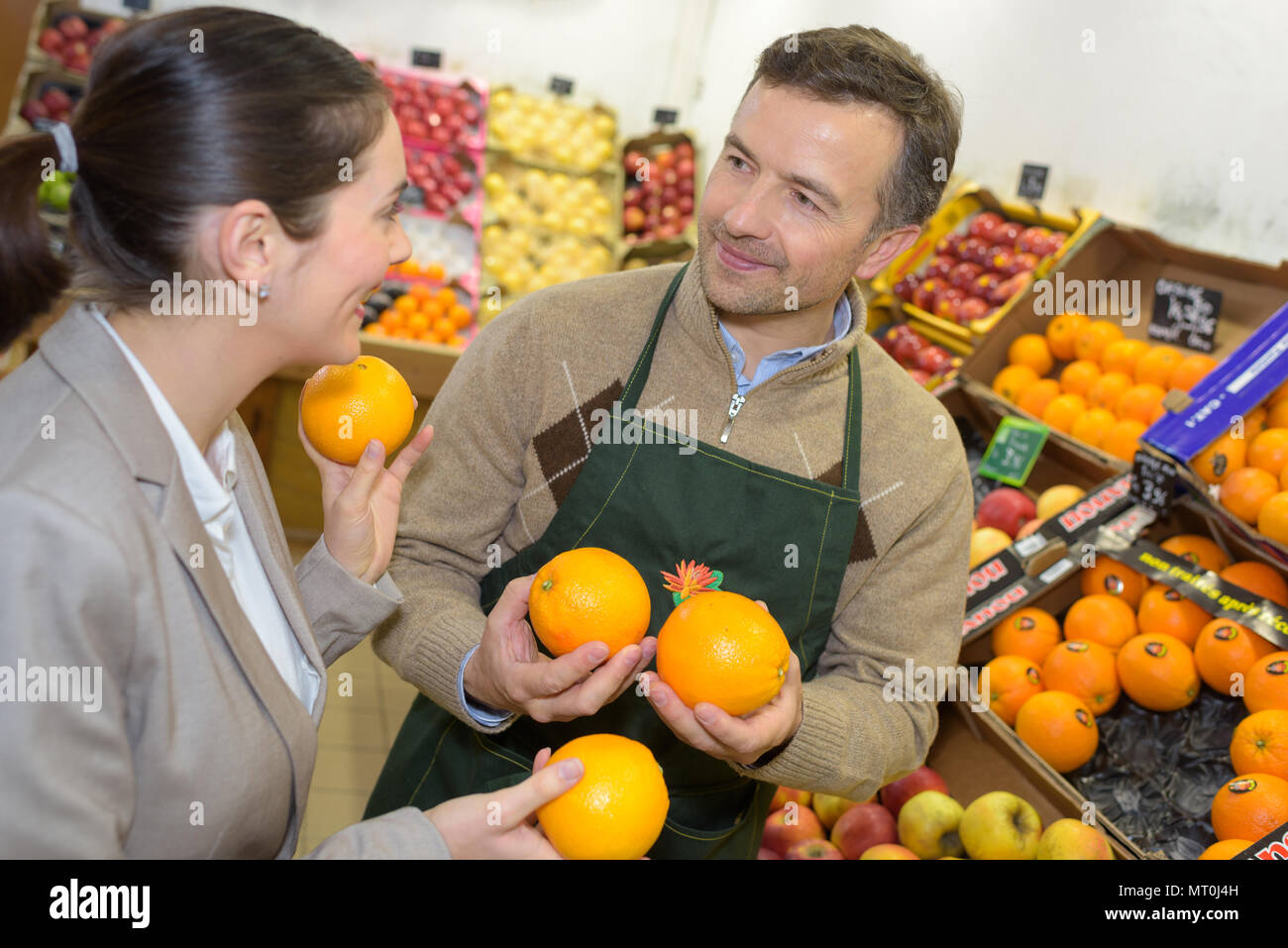 smiling woman choosing different fruits at farm food store display ...