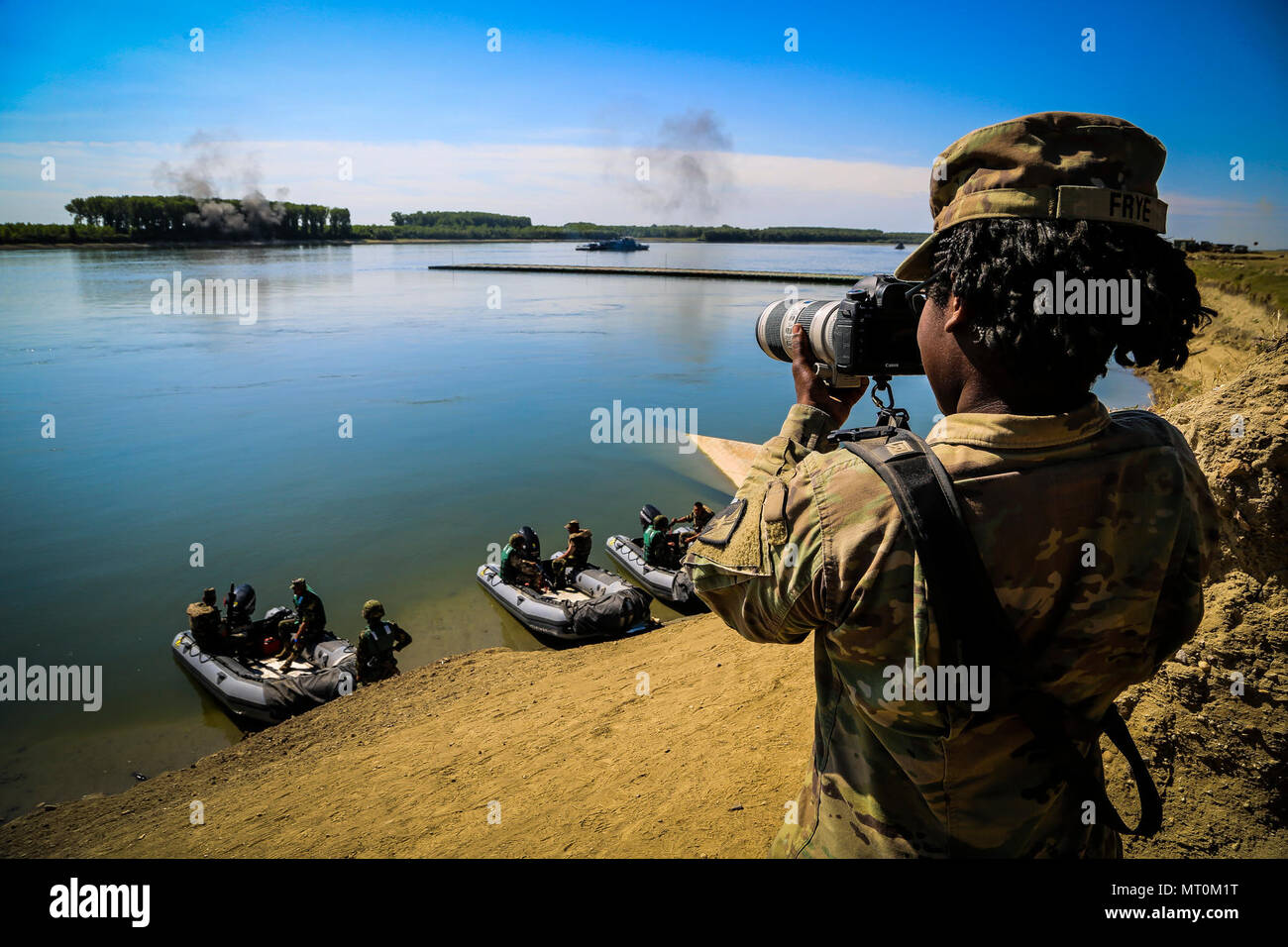 U.S. Army Private First Class Shekinah Frye, photographer assigned to 55th Signal Company (Combat Camera), documents a river crossing exercise during Saber Guardian 17 over the Danube River, Bordusani, Romania, July 15, 2017. Saber Guardian is a U.S. Army Europe-led multinational exercise that spans across Bulgaria, Hungary and Romania with more than 25,000 service members from 22 allied and partner nations. (U.S. Army photo by Staff Sgt. Timothy Villareal/Released) Stock Photo