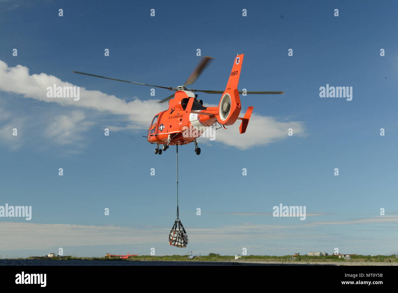 A Coast Guard Air Station Kodiak MH-65 helicopter aircrew, currently deployed on the Coast Guard Cutter Sherman, conducts sling-load operations at Forward Operating Location Kotzebue, July 20, 2017. The aircrew and helicopter are deployed on the Sherman in support of Operation Arctic Shield. U.S. Coast Guard photo by Lt. Brian Dykens. Stock Photo