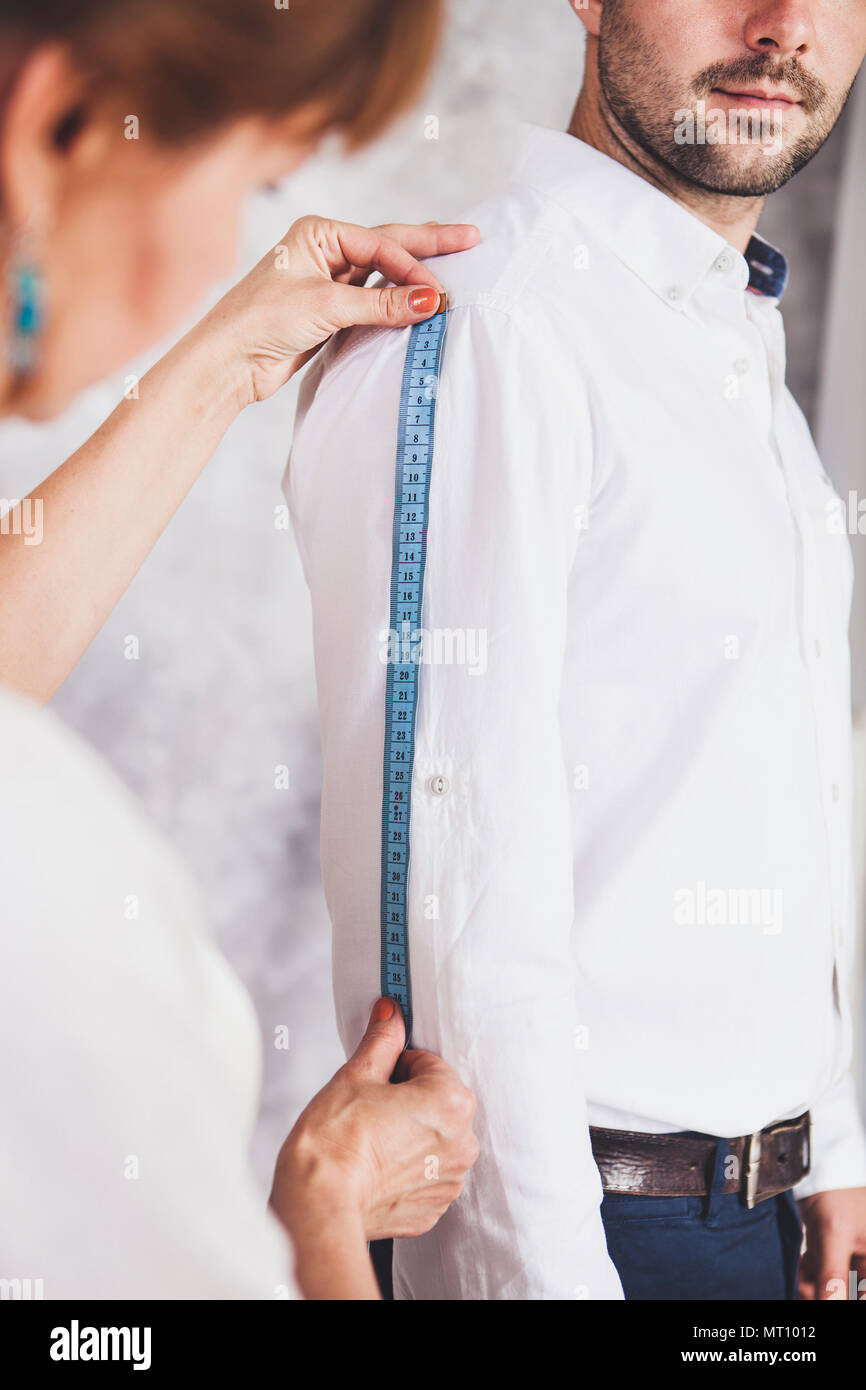 Woman tailor takes measures with male models. Mid section portrait 