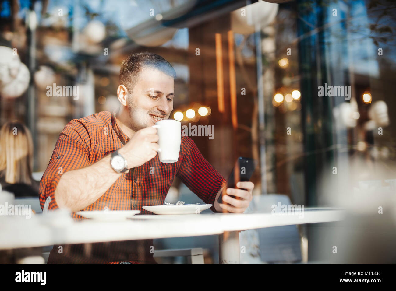 Young attractive man drinking coffee and texting sms at lunch time Stock Photo