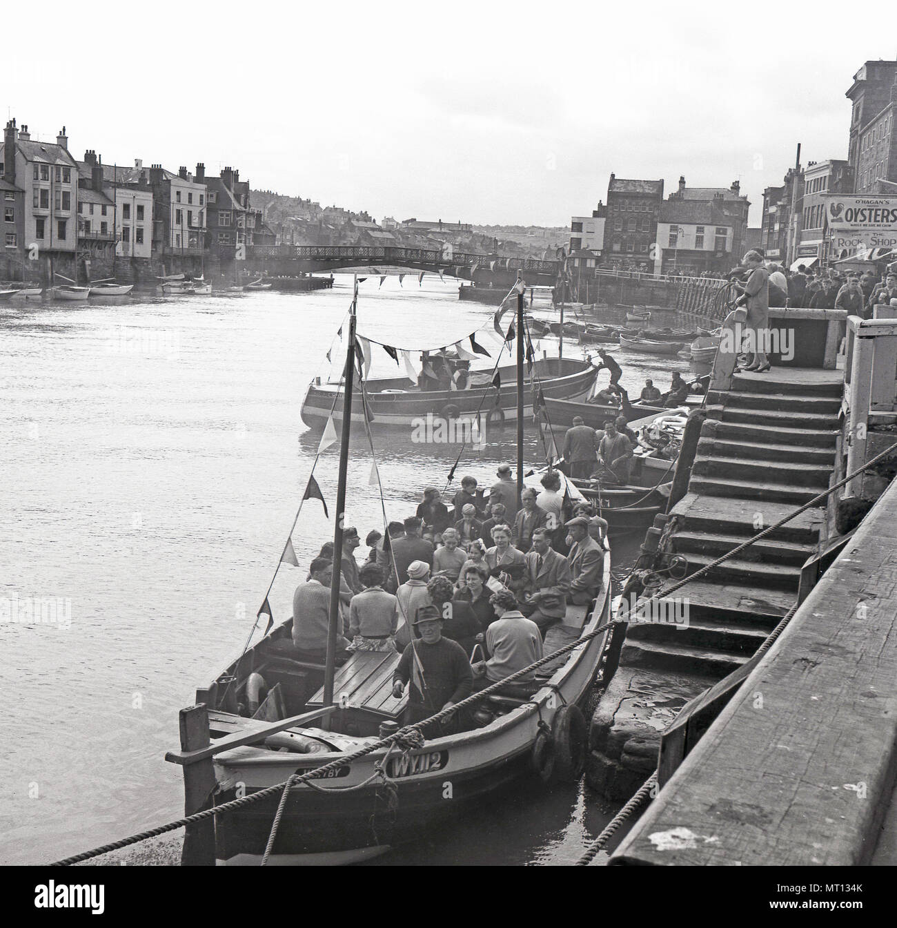 1950s, historical, summer holidaymakers sit in a boat in Whitby harbour before their sea excursion, Whitby, North Yorkshire, England, UK. Stock Photo