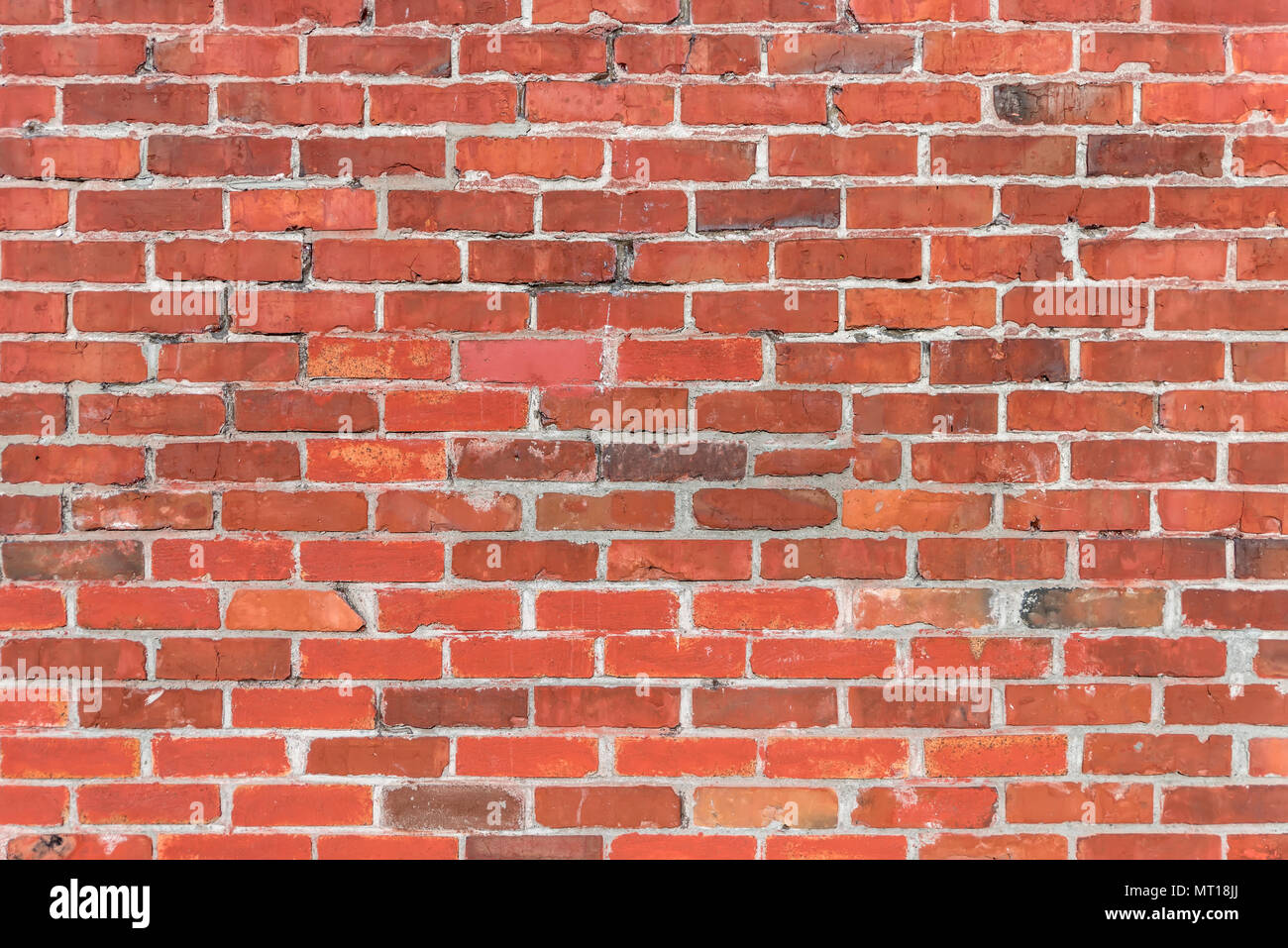 brick wall of red brick with cracks and gray cement between briquettes on a bright, summer day Stock Photo