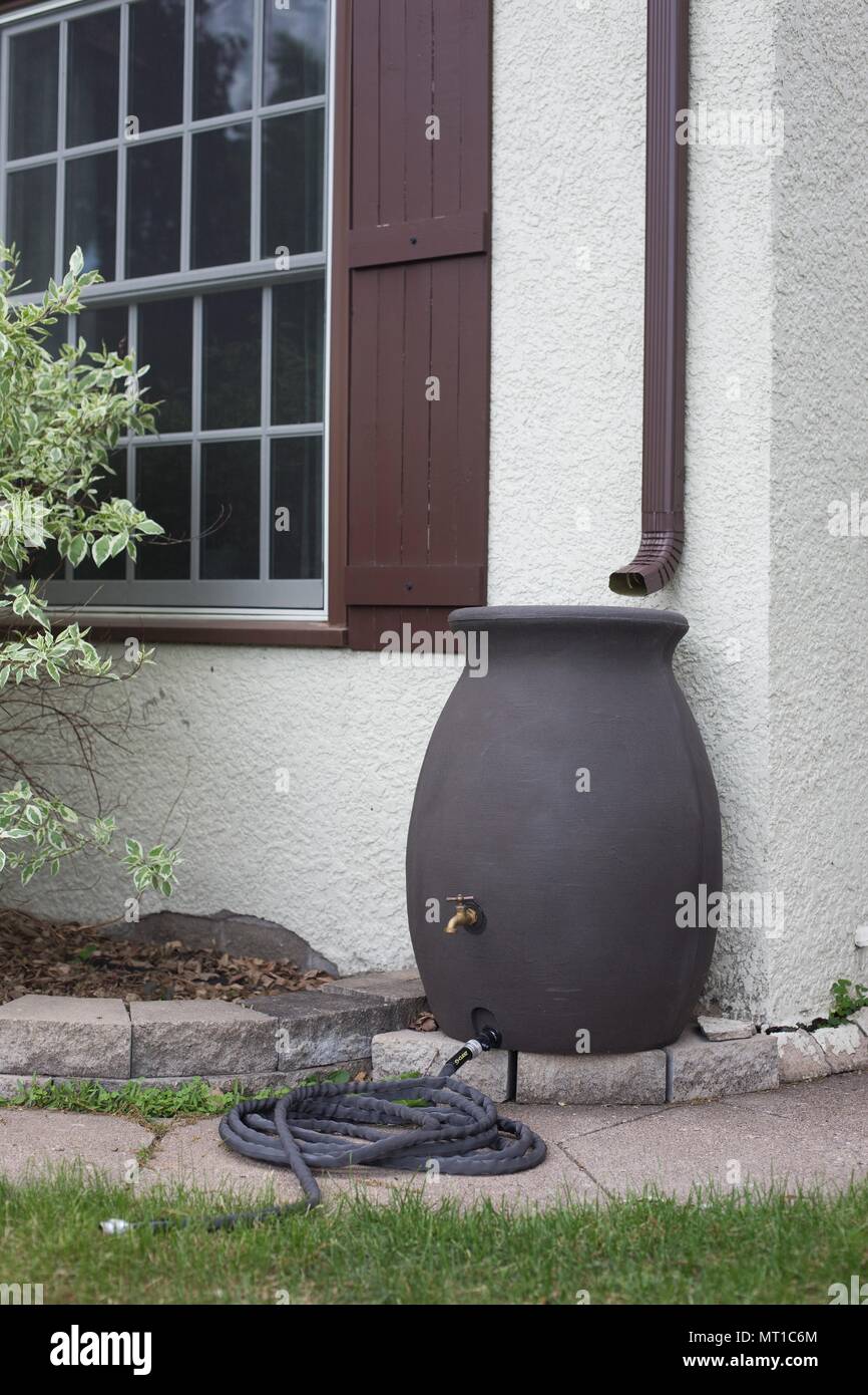 A rain barrel next to a house. Stock Photo