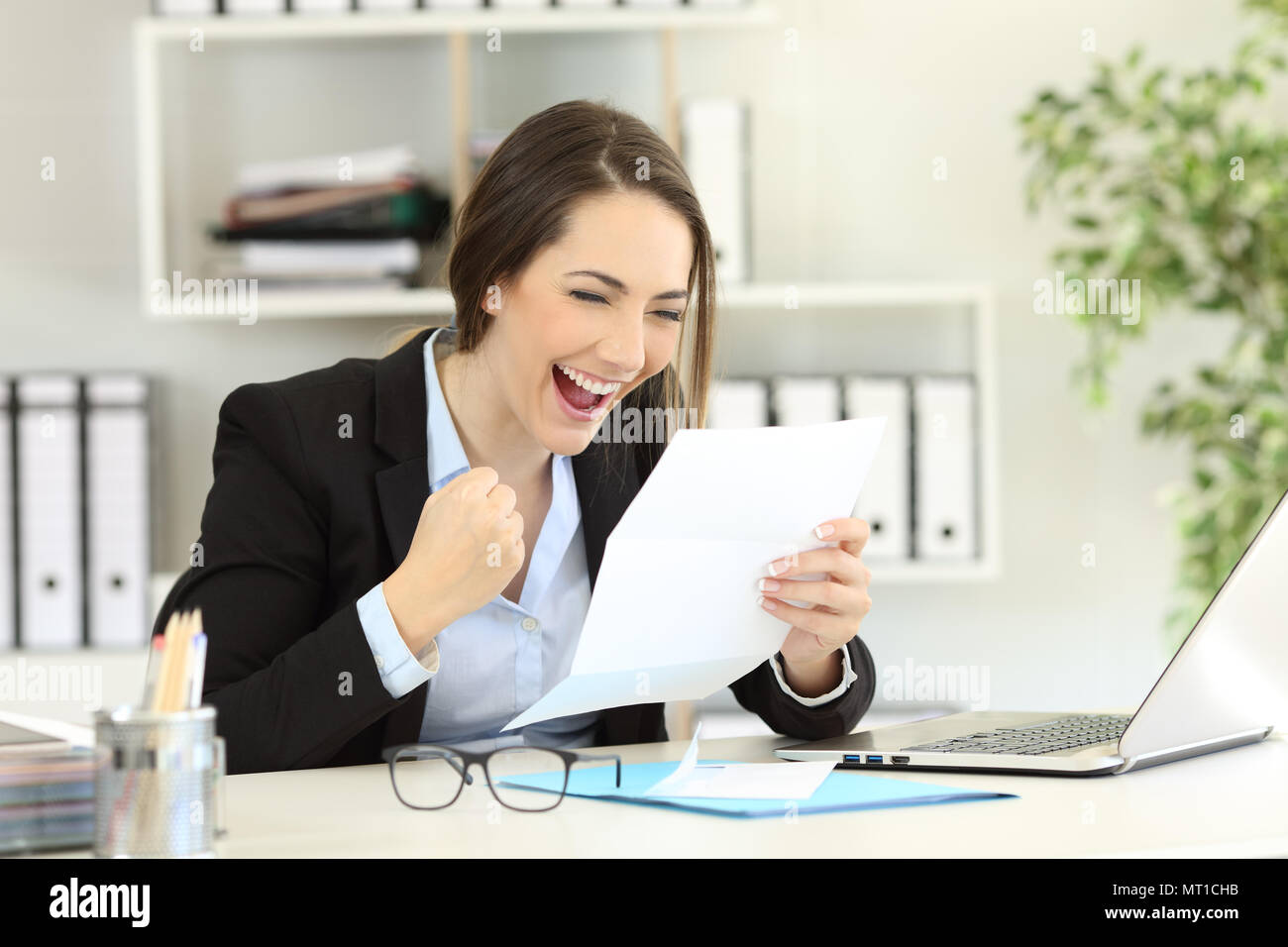 Excited office worker reading good news in a letter Stock Photo